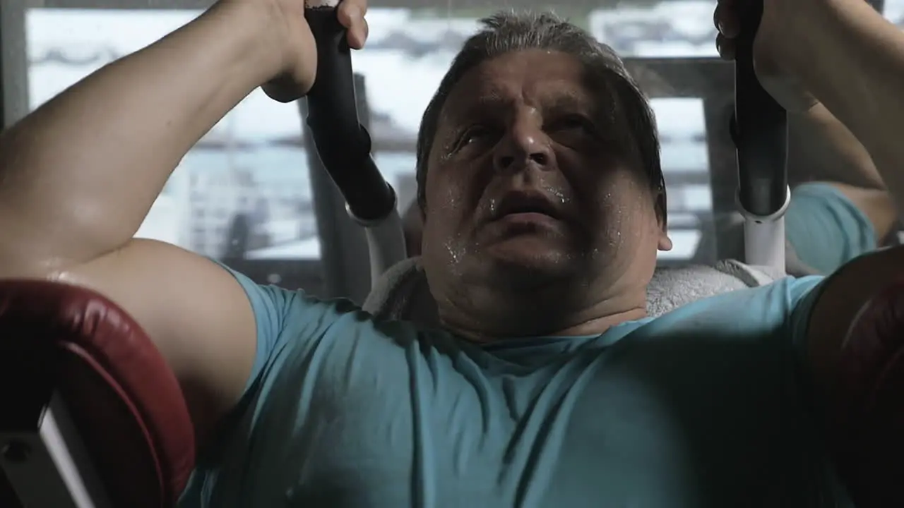 Man exercising hard on strength training machine in the gym