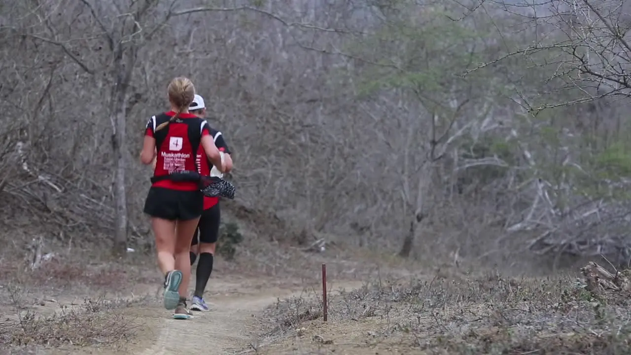 Group of marathon athletes running a charity race on dirt road through forest jungle in rural beautiful nature of Ecuador 50 fps