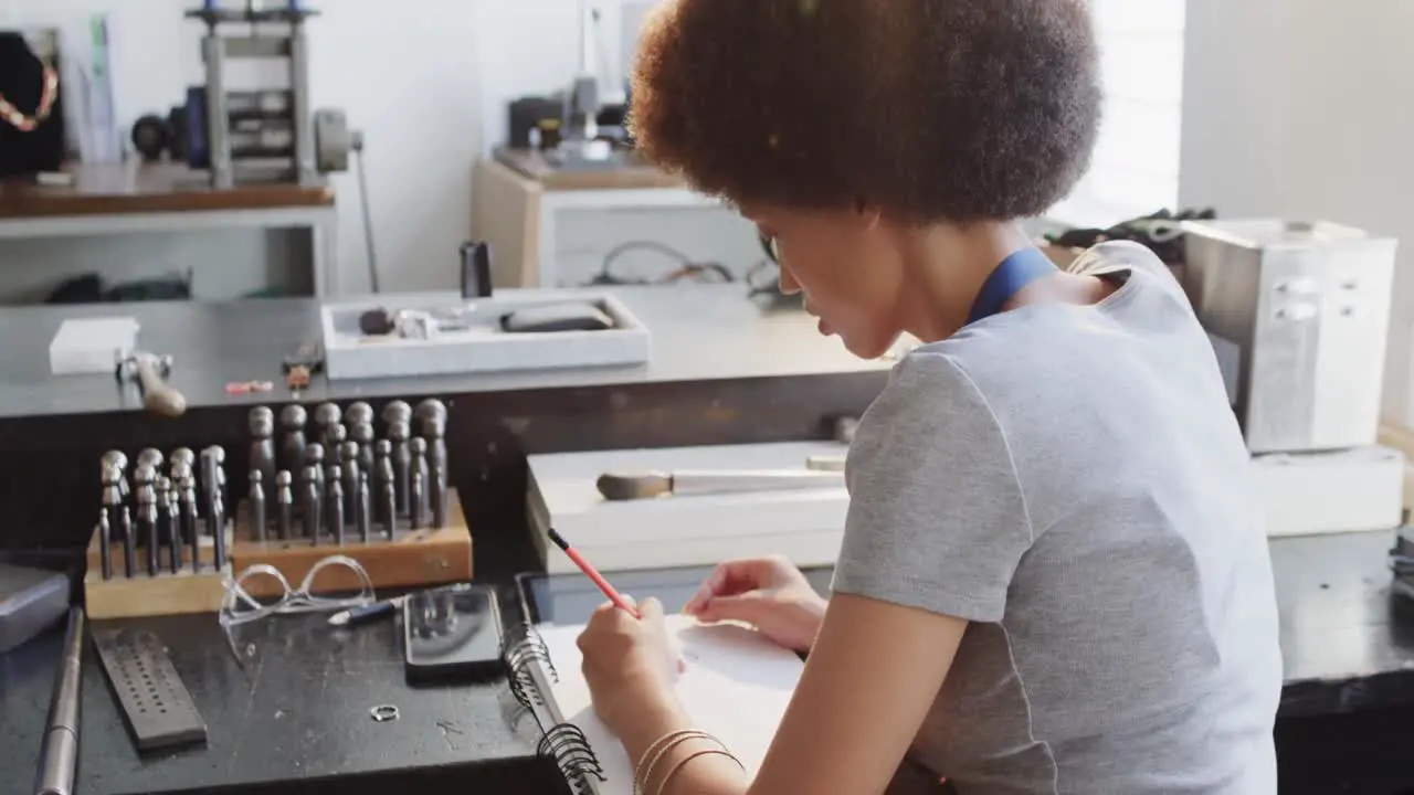 Biracial female worker drawing design of jewellery in workshop in slow motion