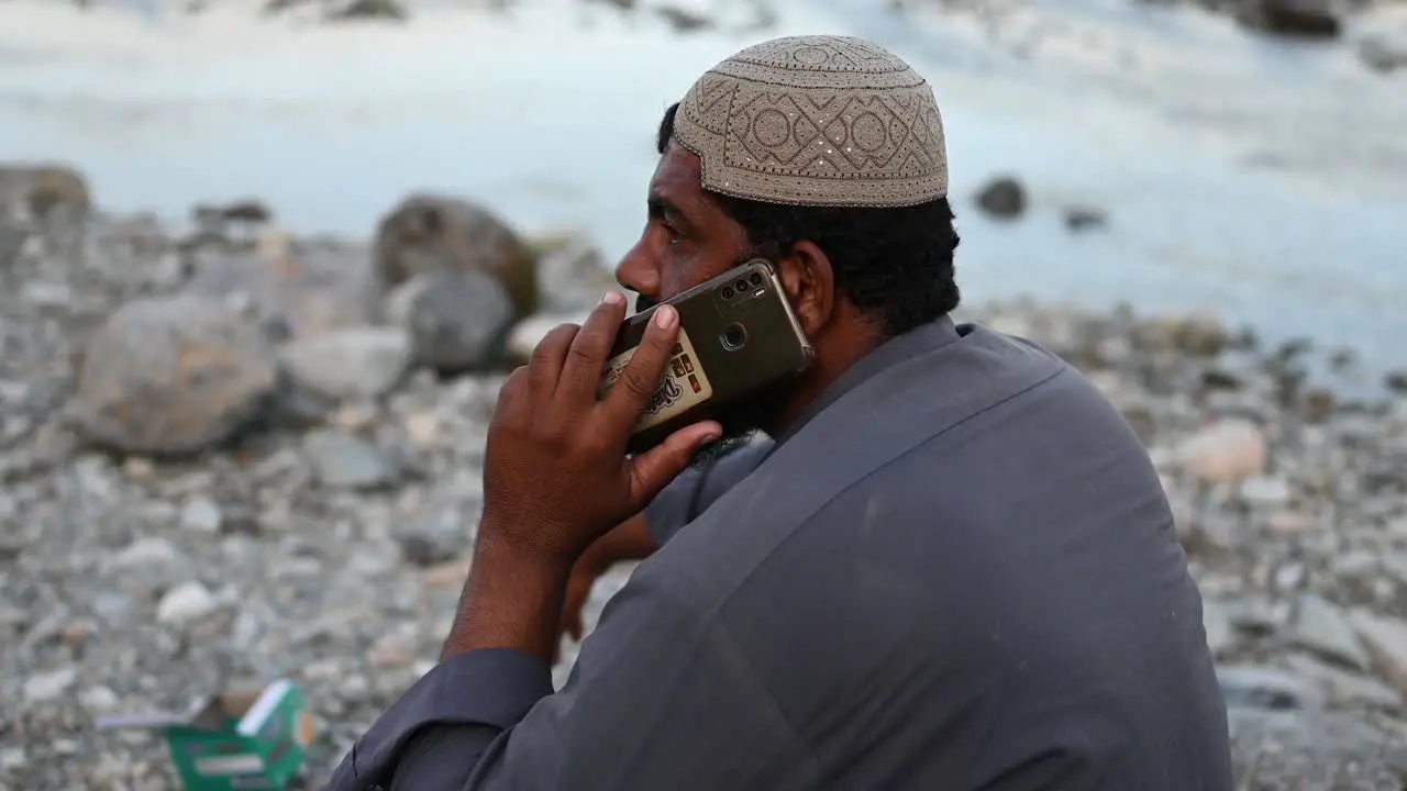 Pakistani Muslim Male Sat Beside River Talking On Mobile Phone In Sindh