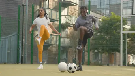 Male And Female Players Exercising And Warming Up On Artificial Soccer Pitch In Urban City Area 