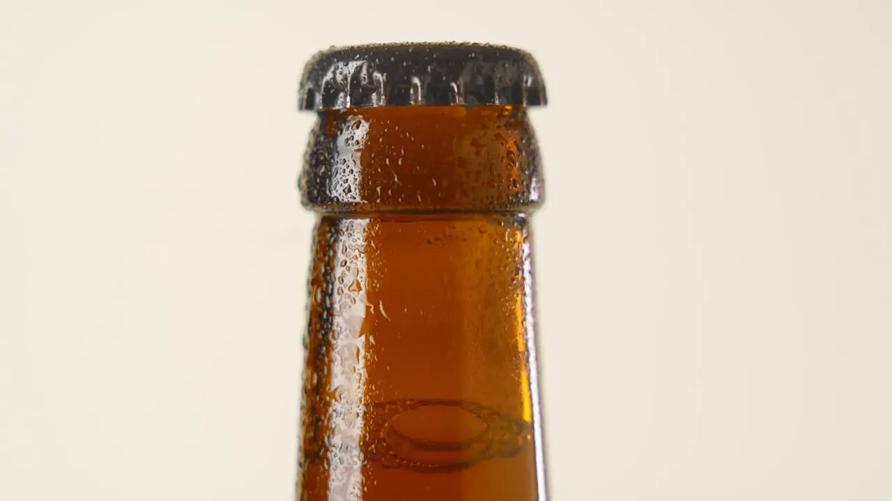 Close-up shot of a slow rotating wet brownisch beer bottleneck