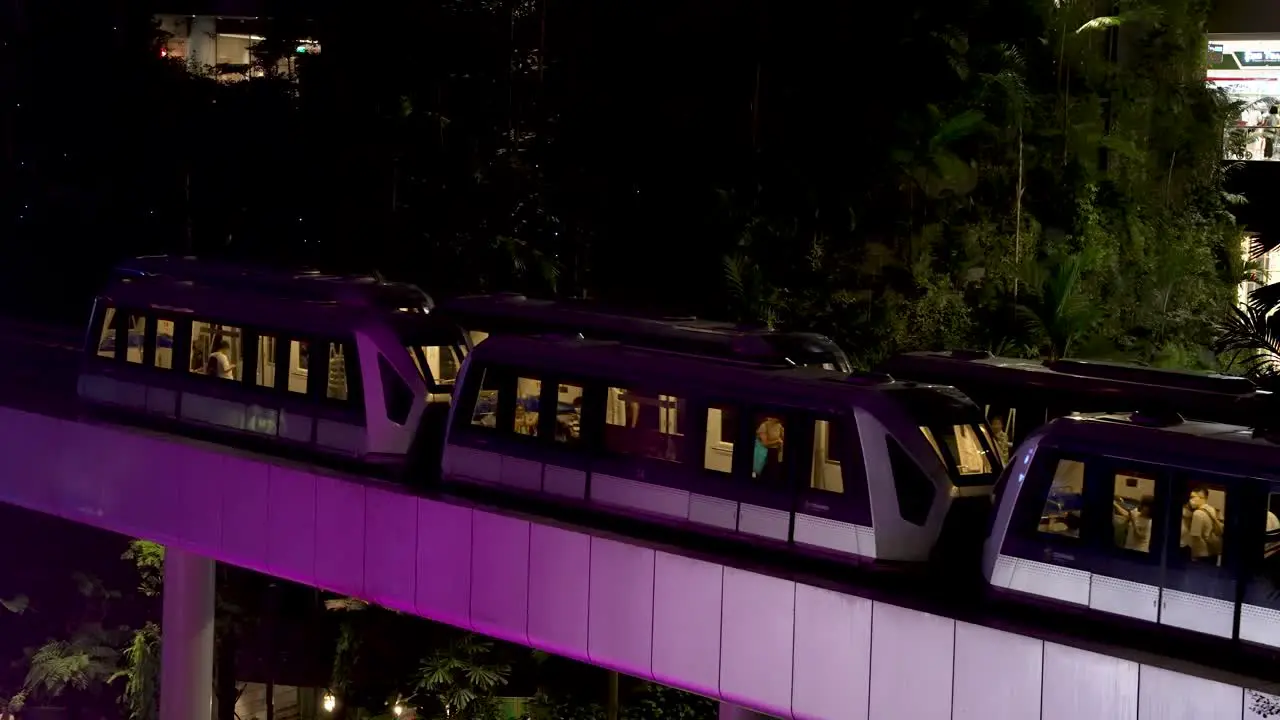 Skytrain's Passing Each Other Inside Jewel Changi Airport Being Illuminated By Purple Light From Waterfall