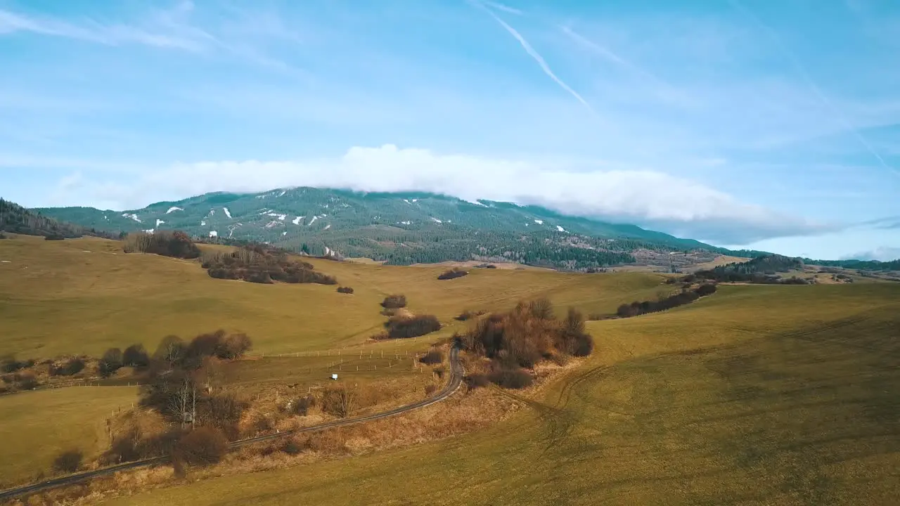 Drone shot over hills with mountain and clouds