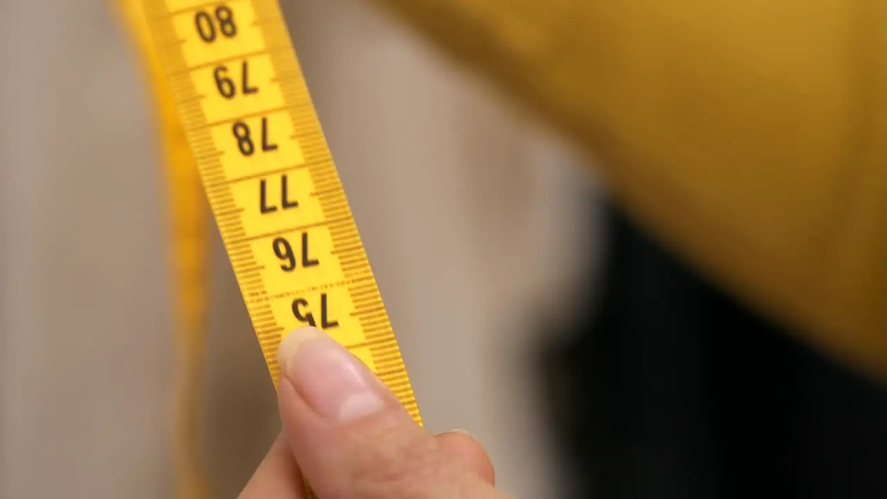 Sliding yellow tape measure through womans hands Slow Motion Closeup