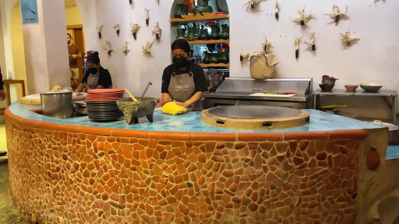 slow motion shot of a couple of cooks making the dough for tortillas on a griddle in oaxaca