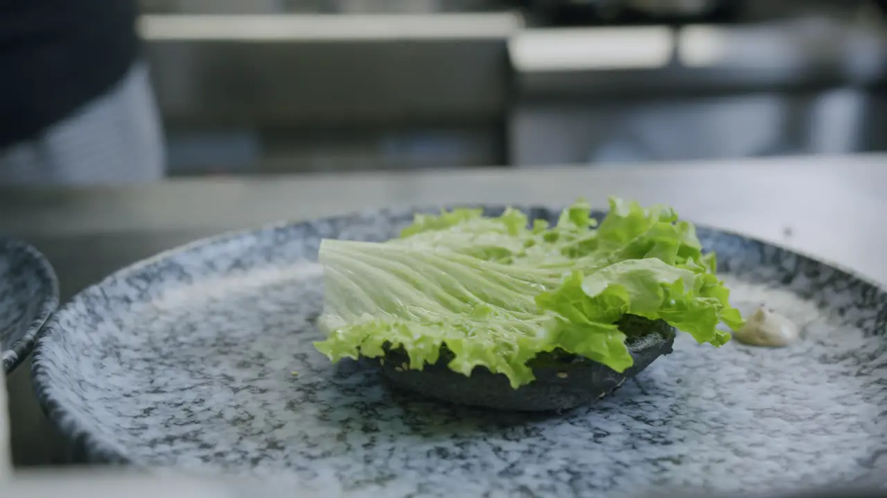 A professional chef is preparing a hamburger in his kitchen 01