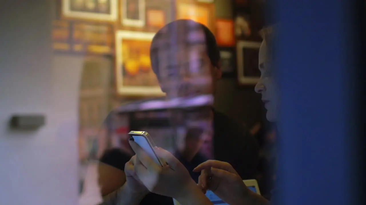 Woman and man talk in the restaurant using smartphone