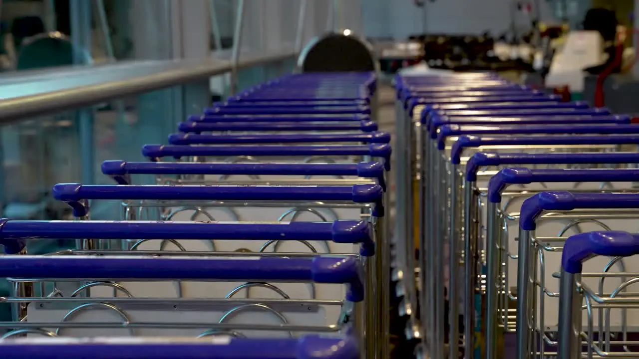 A row of luggage trolleys lock together in a single file for easy usage at an airport terminal