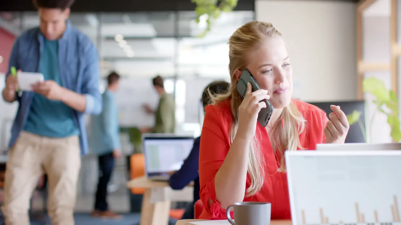 Happy caucasian casual businesswoman talking on smartphone in casual office slow motion