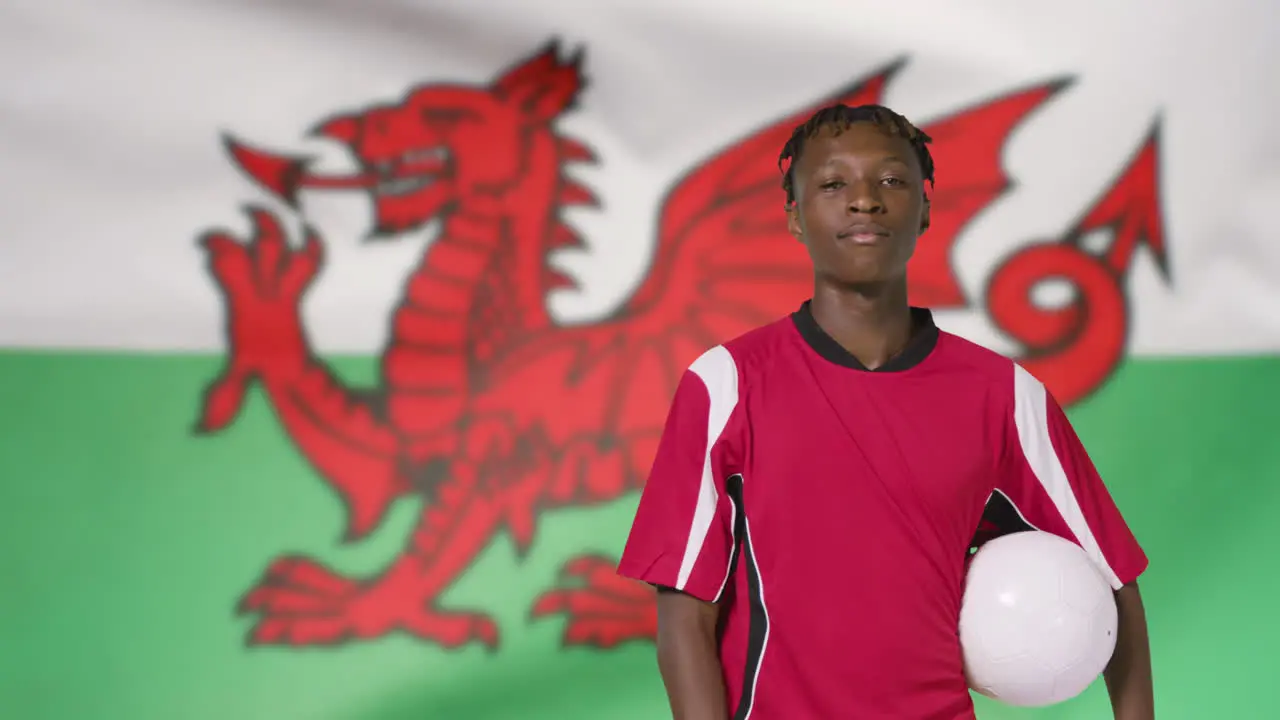 Young Footballer Walking to Camera In Front of Wales Flag 01