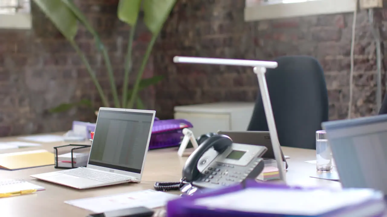 Empty office with technology devices with chart on screen and documents on table in slow motion