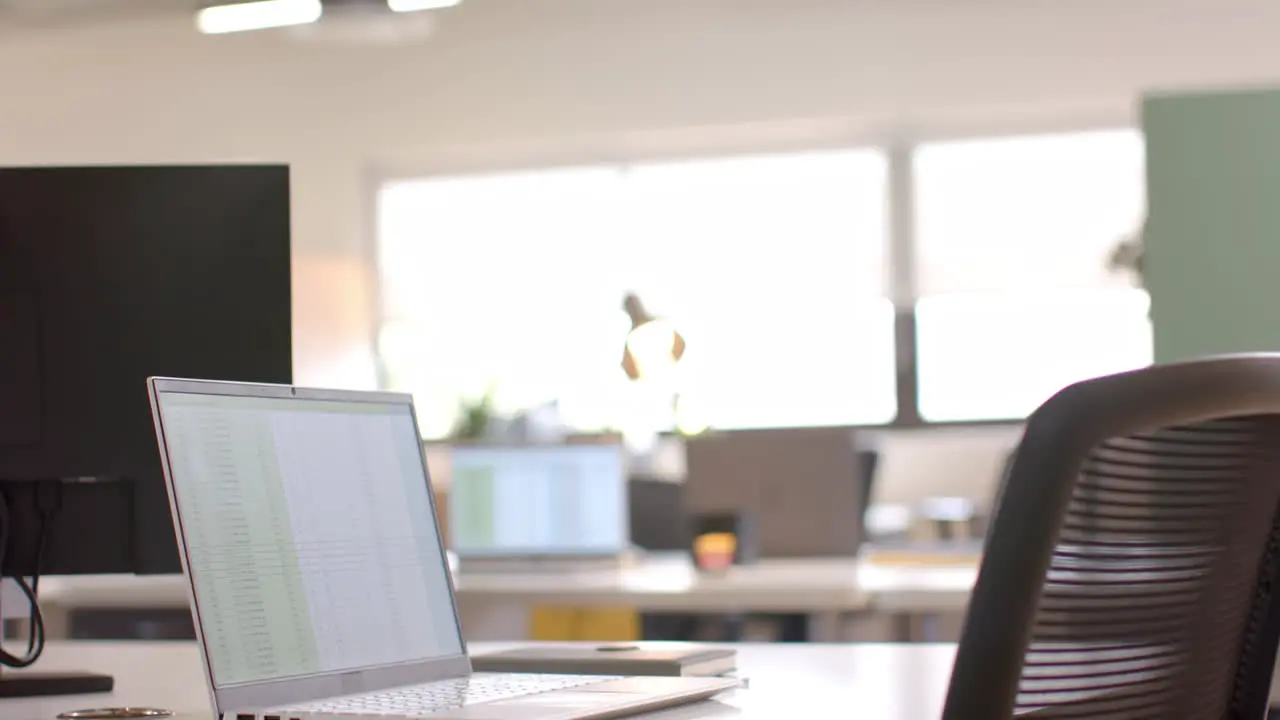 Close up of laptop on desk in sunny office slow motion