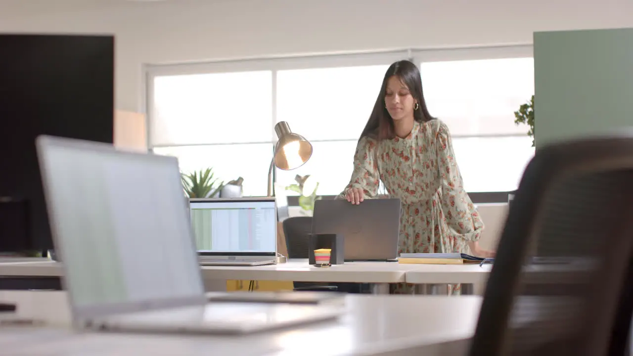 Biracial casual businesswoman closing laptop in office slow motion