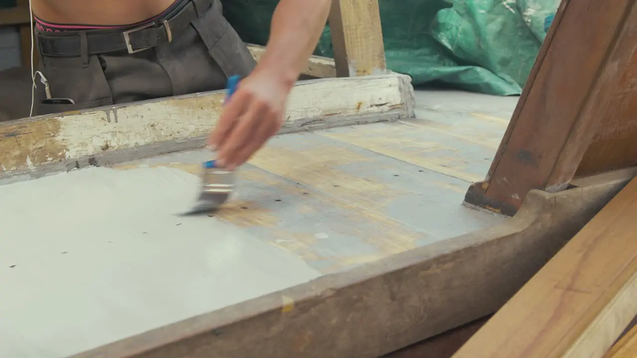 Young man brushing teak timber with aluminium wood primer paint wooden boat maintenance