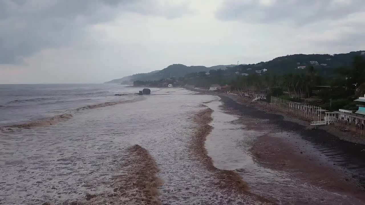 Popular surf spot El Tunco beach in El Salvador during an overcast and cloudy day Low altitude aerial footage Dolly in