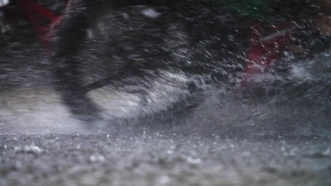 Rain falling on a road pathway in super slow motion as a motorbike drives through