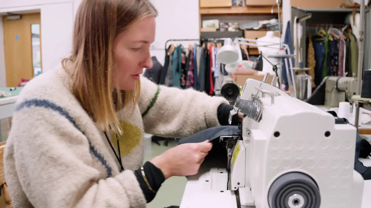 Seamstress using a serger overlock machine in slow fashion textile studio