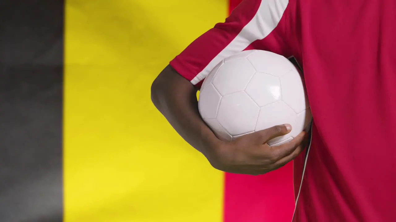 Young Footballer Walking Holding Football In Front of Belgium Flag