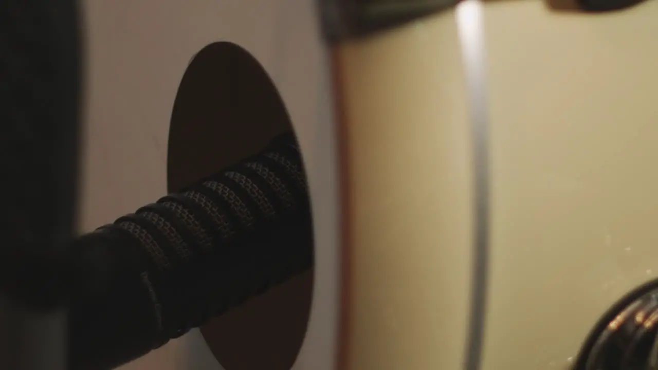 Close up of a dynamic large diaphargm microphone placed in a hole of a bass drum while the drum head is vibrating through playing