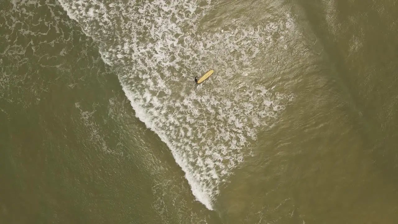 Slow motion of isolated and unrecognizable surfer entering ocean water