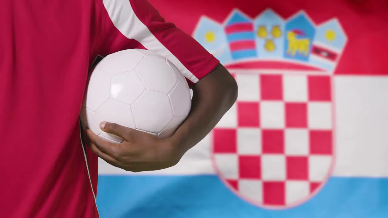 Young Footballer Walking Holding Football In Front of Croatia Flag