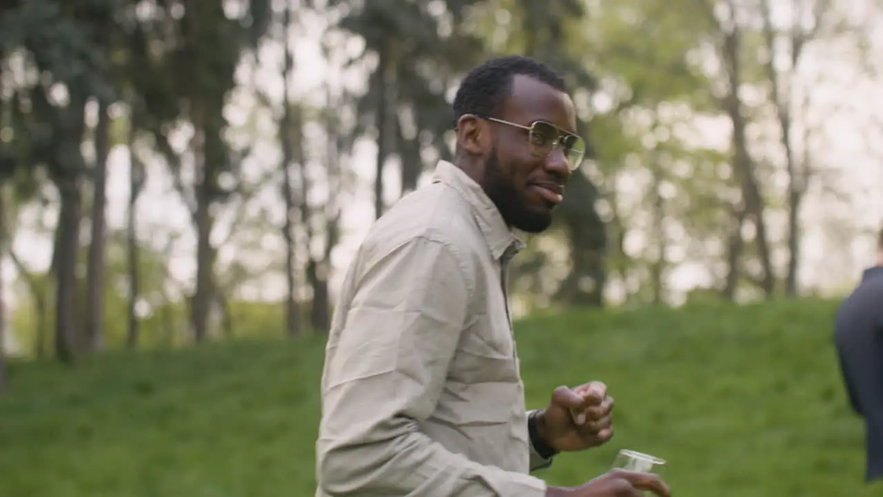 Close Up View Of An Middle Aged Man Dancing While Drinking Wine In The Park