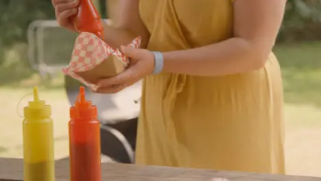 Medium Shot of Festival Goer Adding Sauce to Their Hot Dog