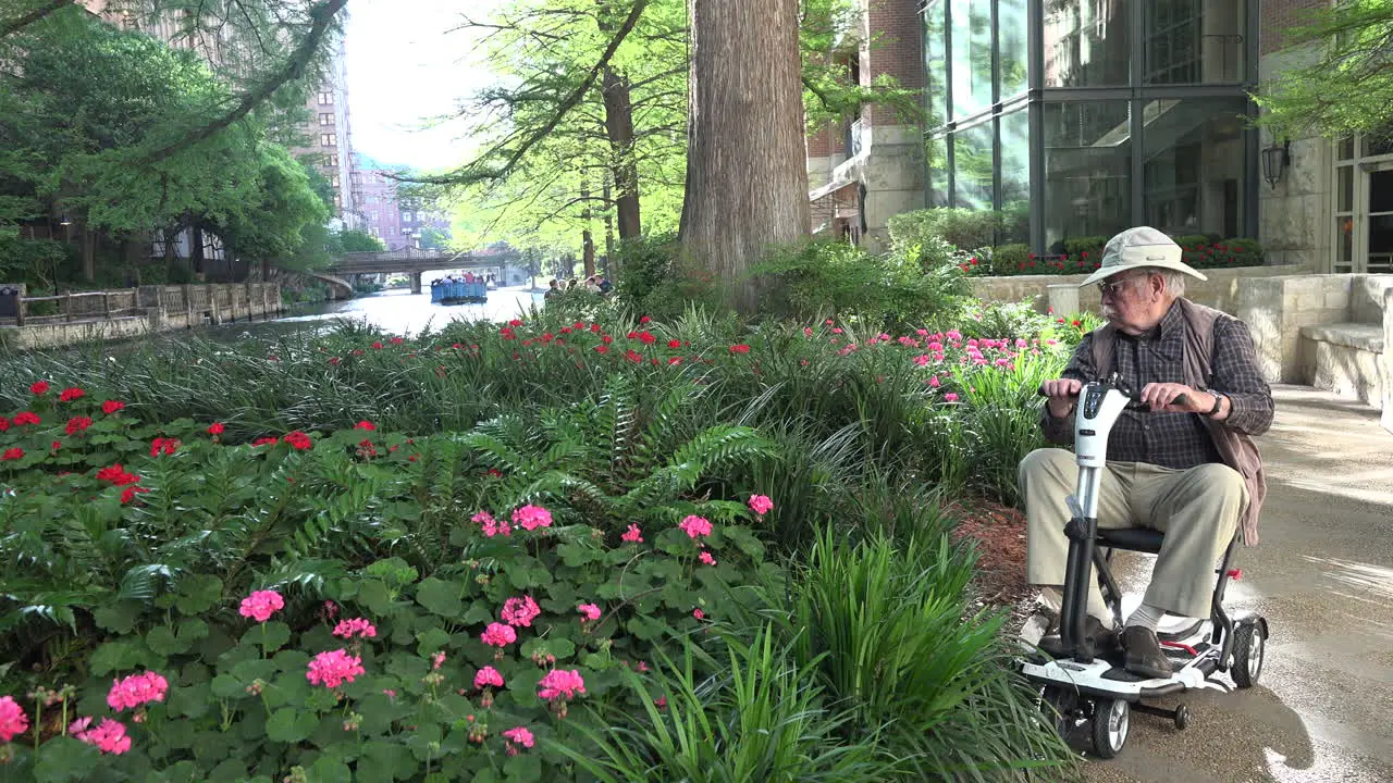 San Antonio man on scooter by flowers on River Walk