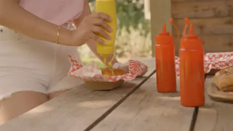 Medium Shot of Festival Goer Adding Some Sauce to a Hot Dog