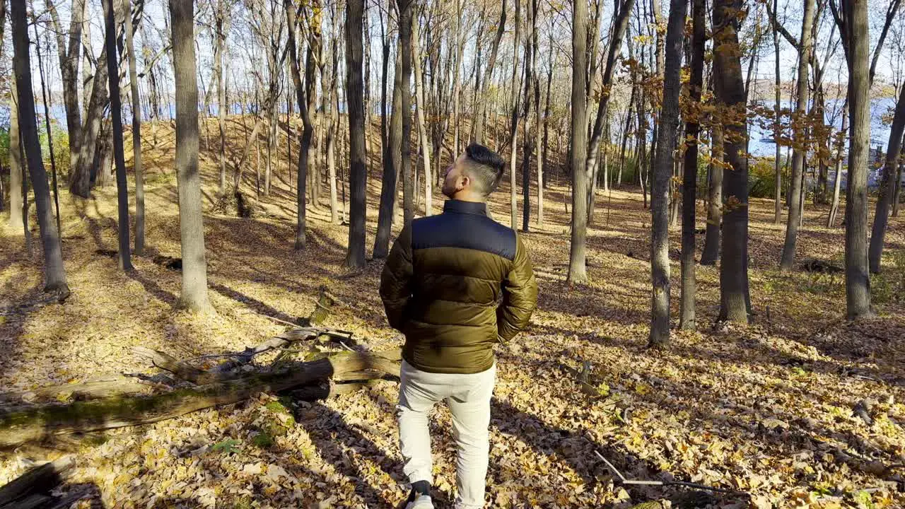 Guy walking on a forest during autumn with a lot of yellow trees leaves