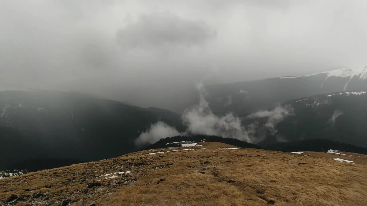 Wide-angle panning right shot of mountain valley landscape with fog and clouds