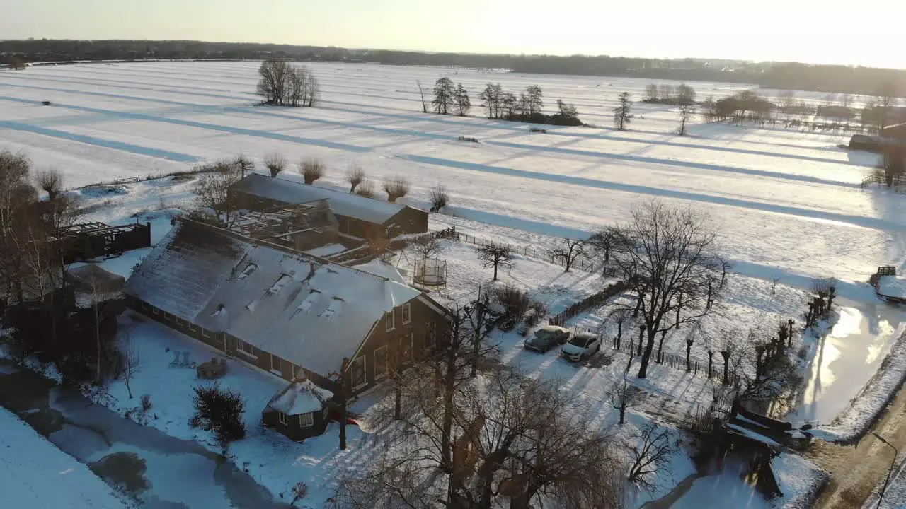 Droneshot of a snowy Dutch landscape with a farm during sunrise