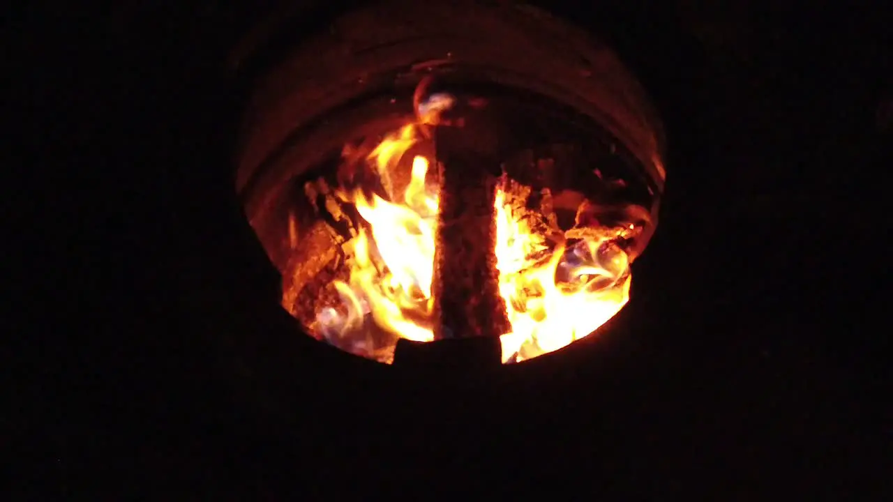 Slow motion burning wood logs on fire in a barrel at night