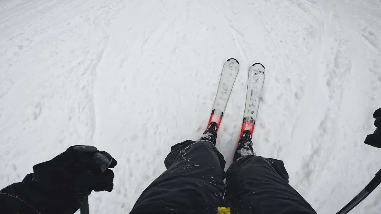 POV Shot Of Skier Skiing Down Snow Covered Slope Looking Down At Skis