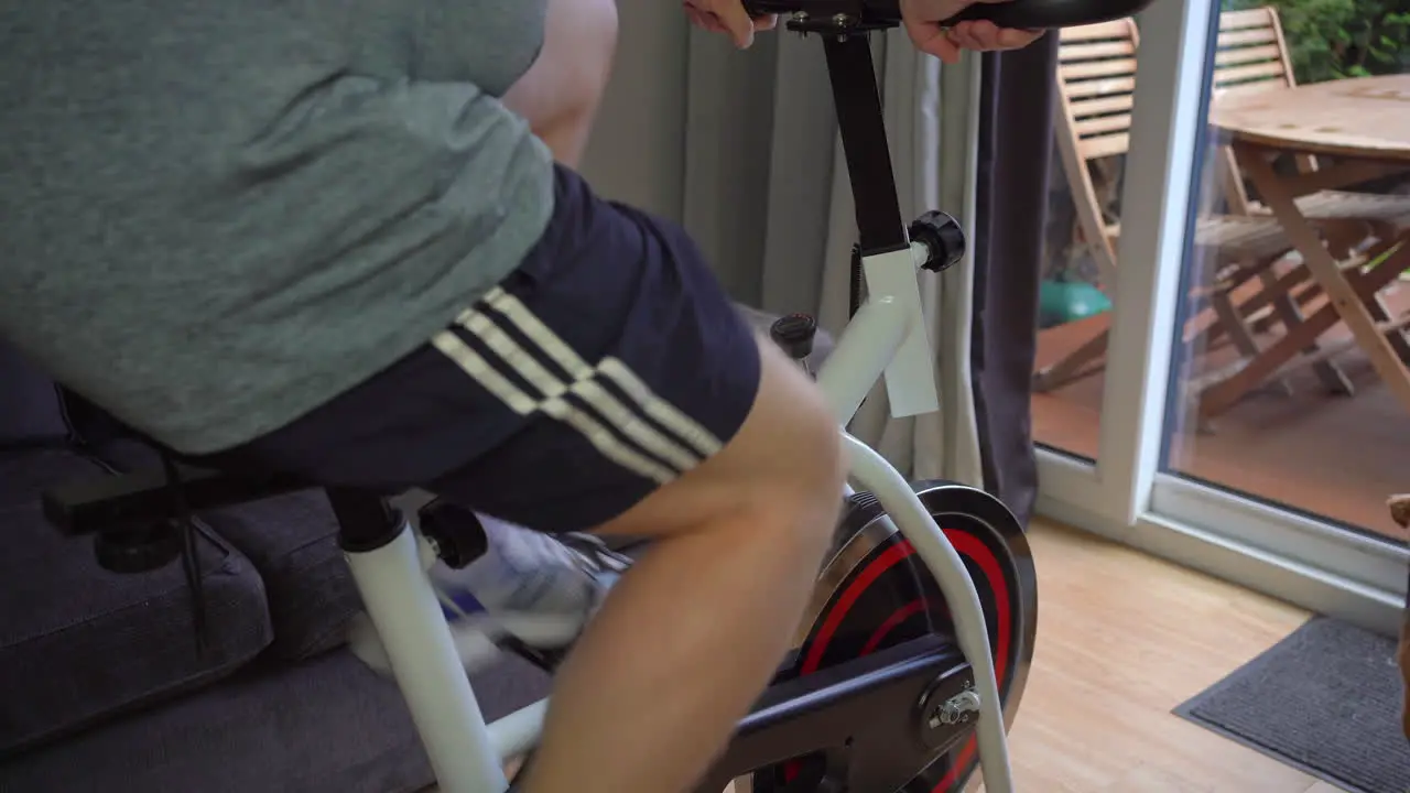 Exercise bicycle at home man pedals while small dog watches