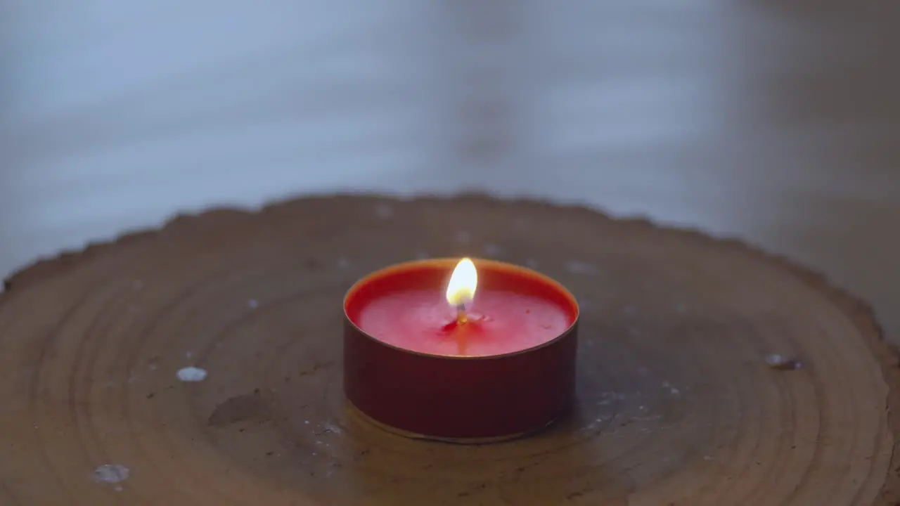 Red Candle sitting on a wooden plank being lit and burning