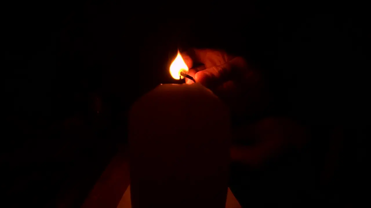 Lighting a candle with a match in the dark