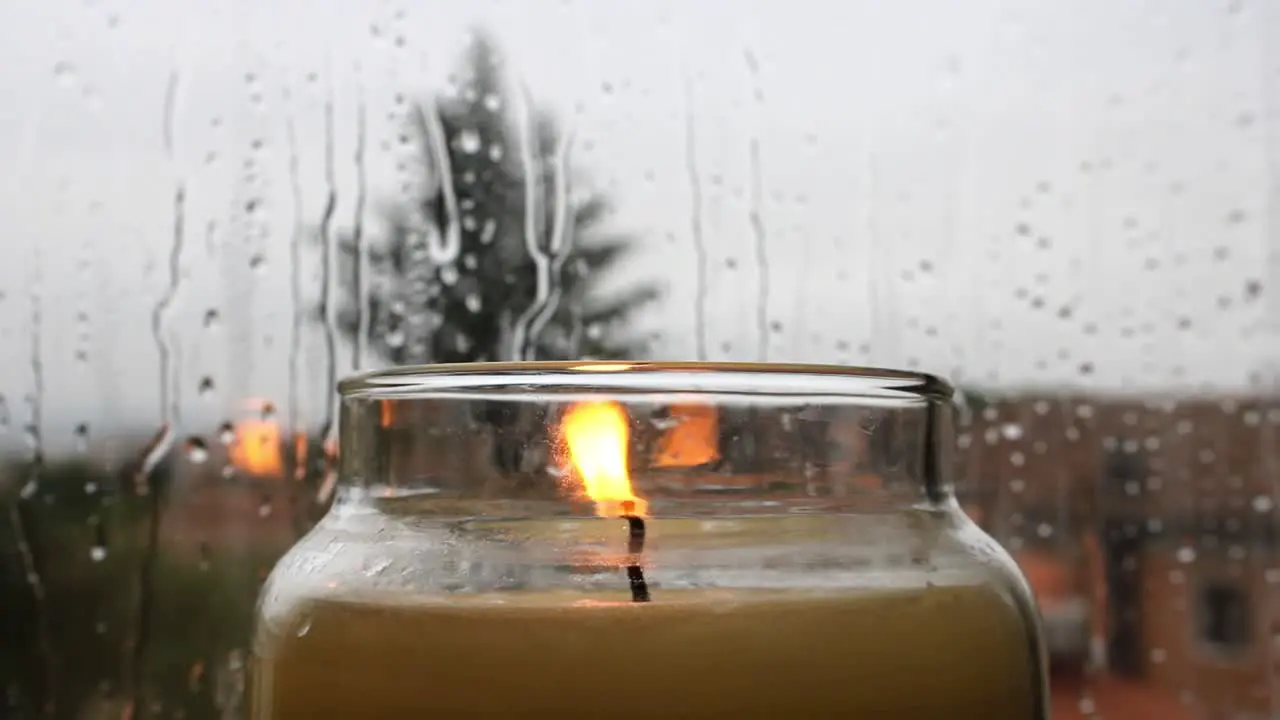 Zen background of a burning candle in front of a window during a rainy and moody day no people