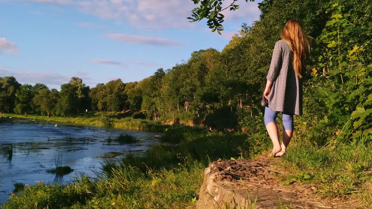 Caucasian woman standing barefoot at the edge of a beautiful lake at Bauska Latvia