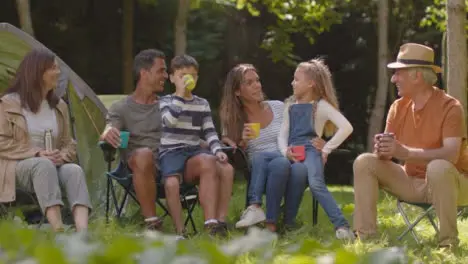 Long Shot of Family On Camping Trip Sitting By Their Tents 01