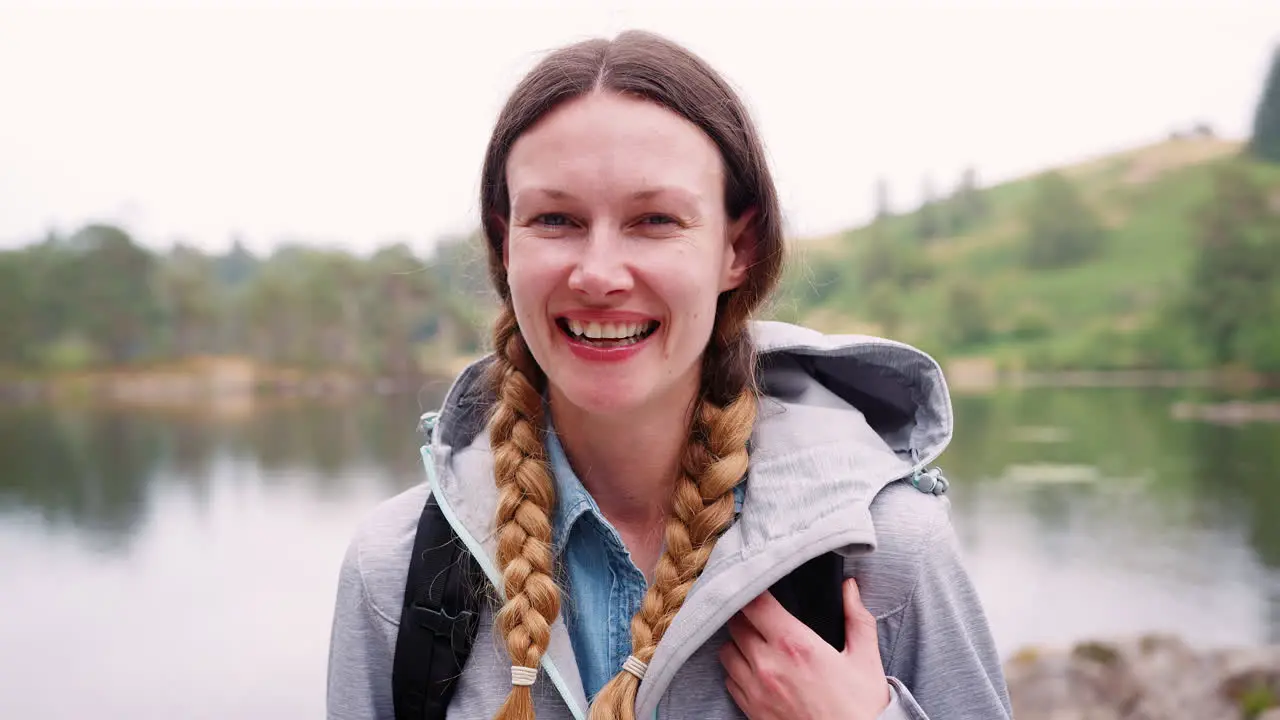 Young adult woman on a camping holiday standing by a lake laughing close up Lake District UK