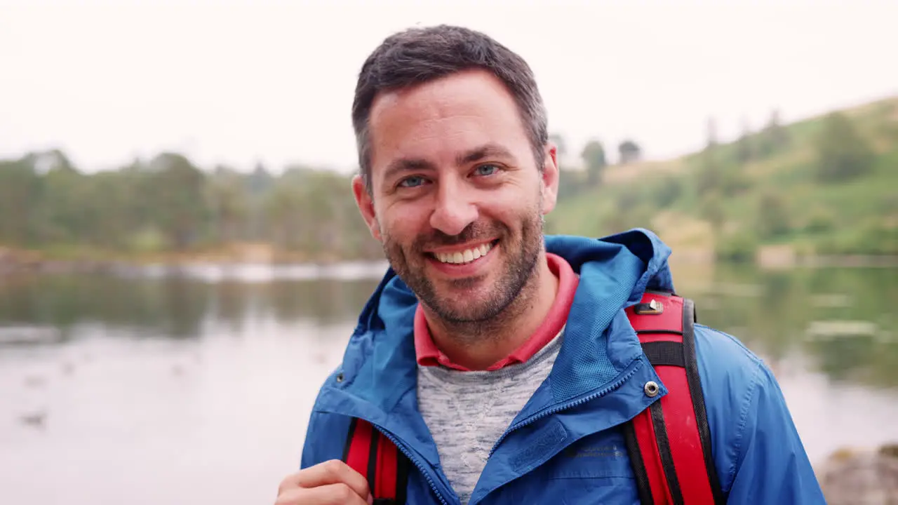 Adult man on a camping holiday standing by a lake smiling close up Lake District UK