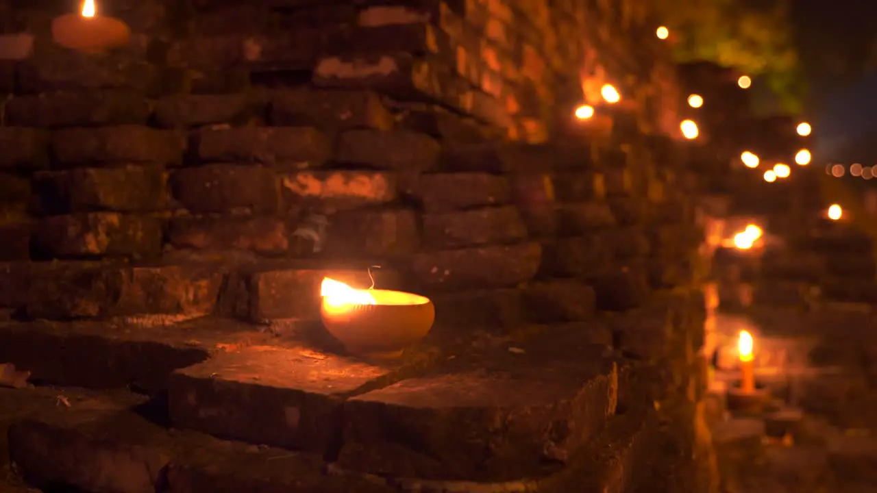 Beautiful decorative candles burning on stone walls at night