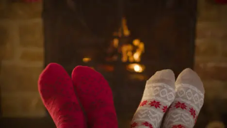 Close Up Shot of Couples Feet In Front of a Cosy Burning Fireplace