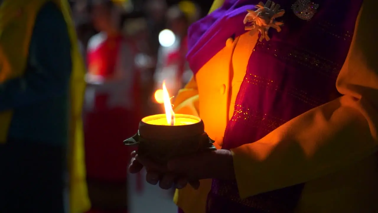 Cinematic push in towards female hands holding stone candle burning at night