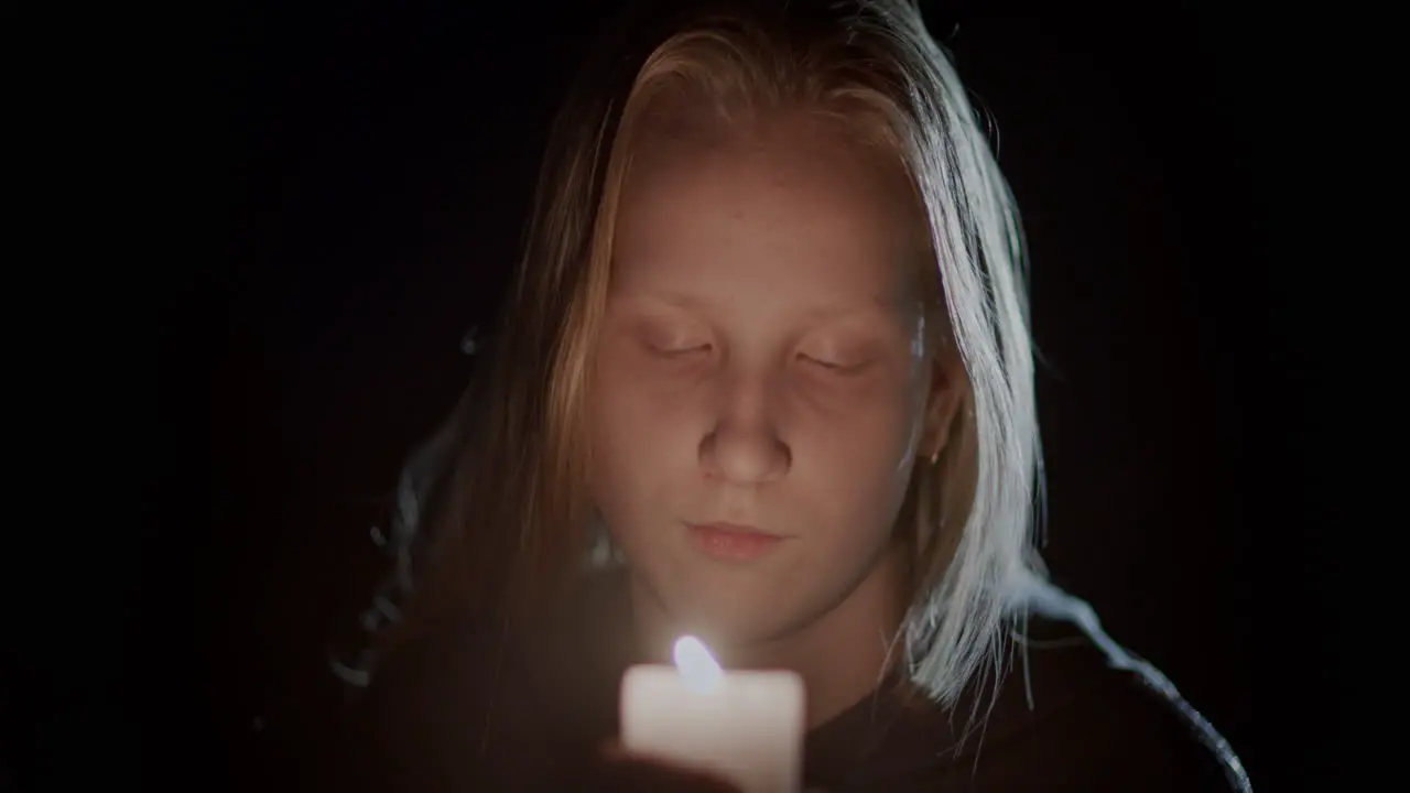 Face of a child looking at a candle burning in the dark