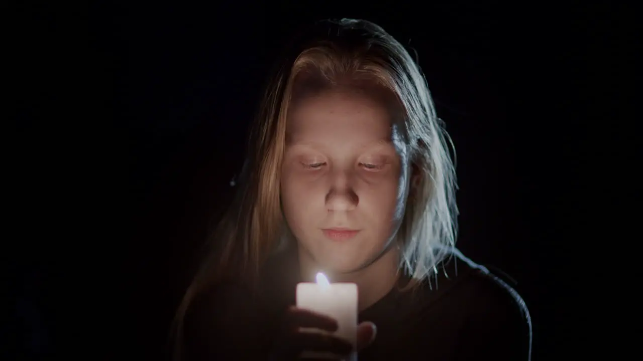 Portrait of a child looking at a candle burning in the dark