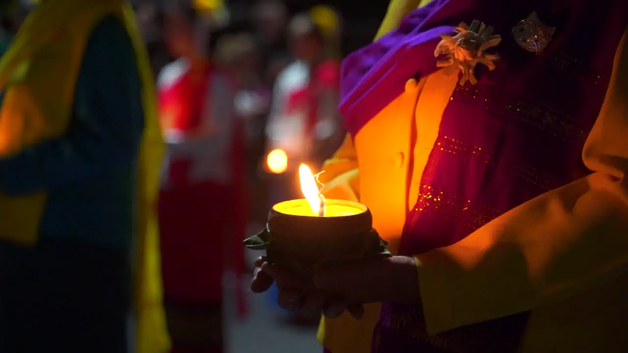 Cinematic Push in toward woman in traditional clothes holding burning candle at night