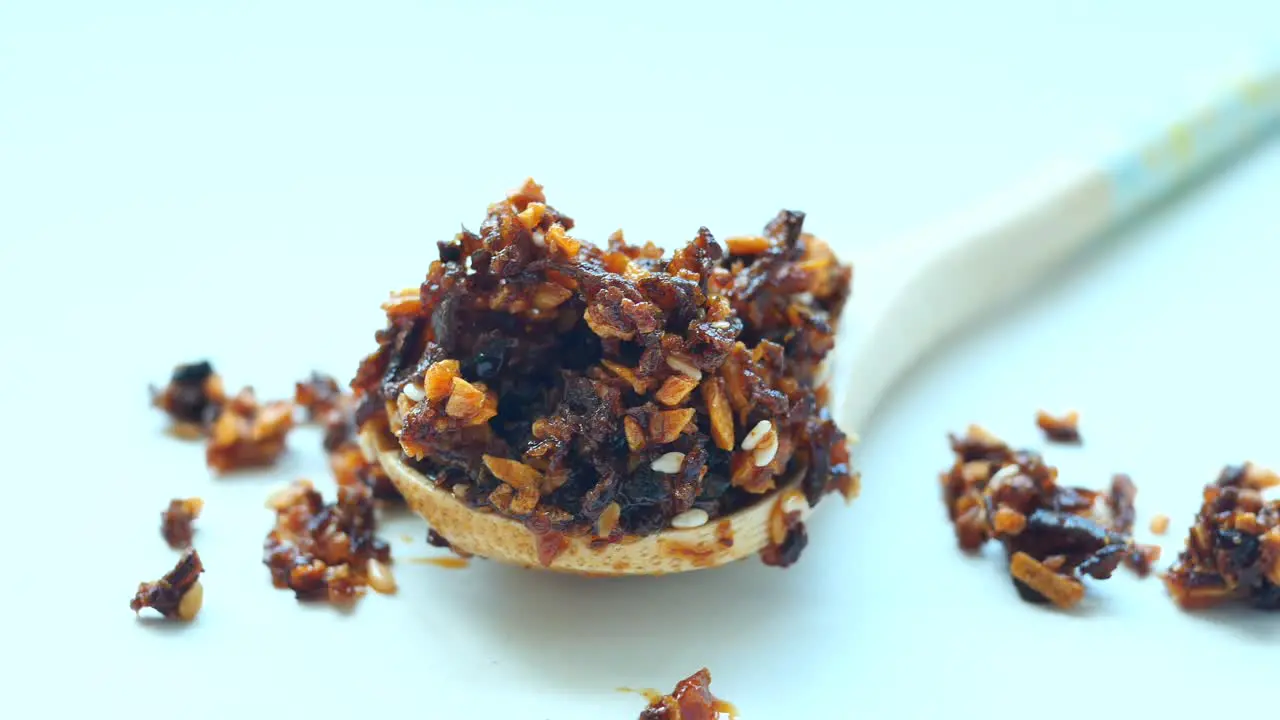 Chili and garlic flakes on wooden spoon on white background